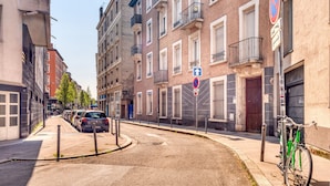 Une rue bordée de voitures garées, avec un vélo et des immeubles dotés de balcons.
