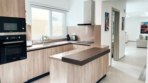 A modern kitchen with built-in appliances, a large window, and a view of the living area.