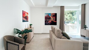 A modern living room with a sofa, a chair, a cabinet, and two paintings on the wall.