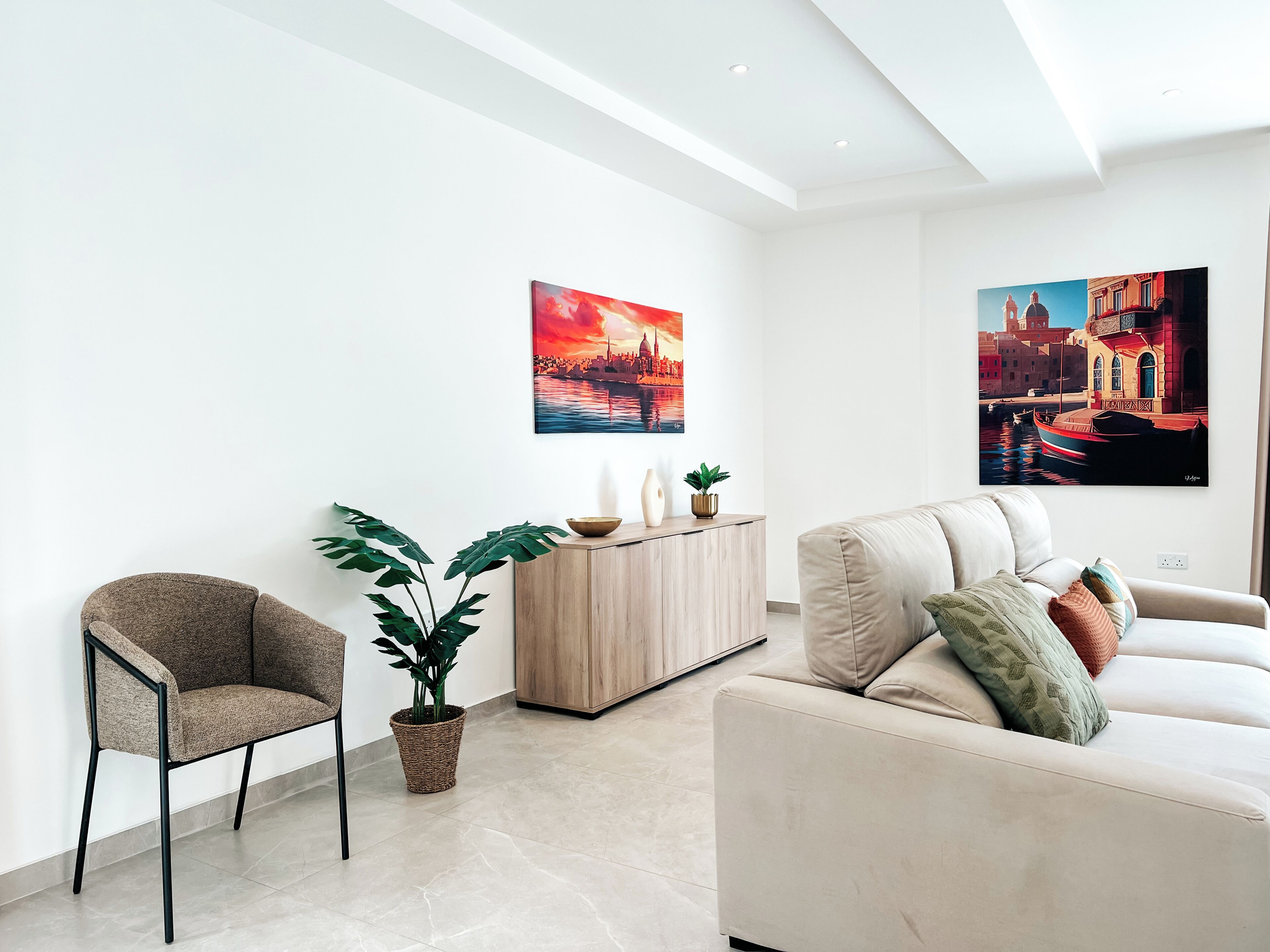 Una sala moderna con sofá, sillón y una planta en maceta.