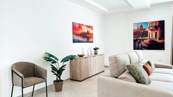 Una sala moderna con sofá, sillón y una planta en maceta.