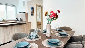 A modern dining area with a wooden table set for four, surrounded by upholstered chairs.