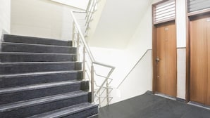 A staircase with metal railings, a wooden door, and a tiled floor. - Deluxe Cybercity U19 (Gurugram)