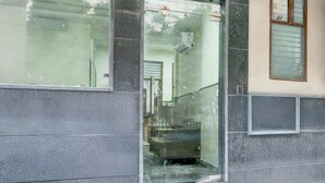 A building entrance with a glass door, a metal staircase, and a small window on the right. - Deluxe Cybercity U19 (Gurugram)