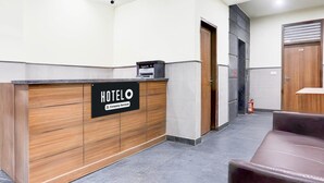 A reception desk with a sign reading 'HOTELO,' a fire extinguisher, and a brown leather couch. - Deluxe Cybercity U19 (Gurugram)