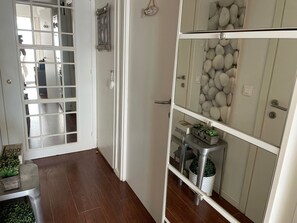 A hallway with a wooden floor, a white door with a frosted glass panel, and a white cabinet with decorative items. - SUPERB WATERFRONT SEA/MOUNTAIN APARTMENT. EXCEPTIONAL SEA VIEW! (Saint-Raphaël)