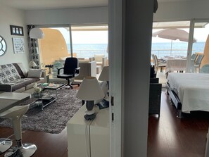 A modern hotel room with a large window offering a sea view, a sofa, a dining area, and a bed. - SUPERB WATERFRONT SEA/MOUNTAIN APARTMENT. EXCEPTIONAL SEA VIEW! (Saint-Raphaël)