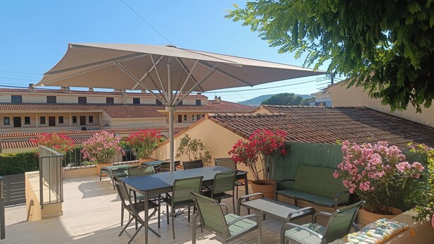 An outdoor patio with a table and chairs, surrounded by potted plants and flowers. - Sea view apartment - XXL terrace - Beach 30 m away (Saint-Raphaël)