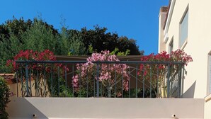 A gated entrance with a metal gate, a red and white sign, and a balcony with pink flowers. - Sea view apartment - XXL terrace - Beach 30 m away (Saint-Raphaël)