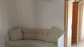 A modern, minimalist room with a built-in sofa, a striped rug, and a wooden door leading to another room. - Sea view apartment - XXL terrace - Beach 30 m away (Saint-Raphaël)