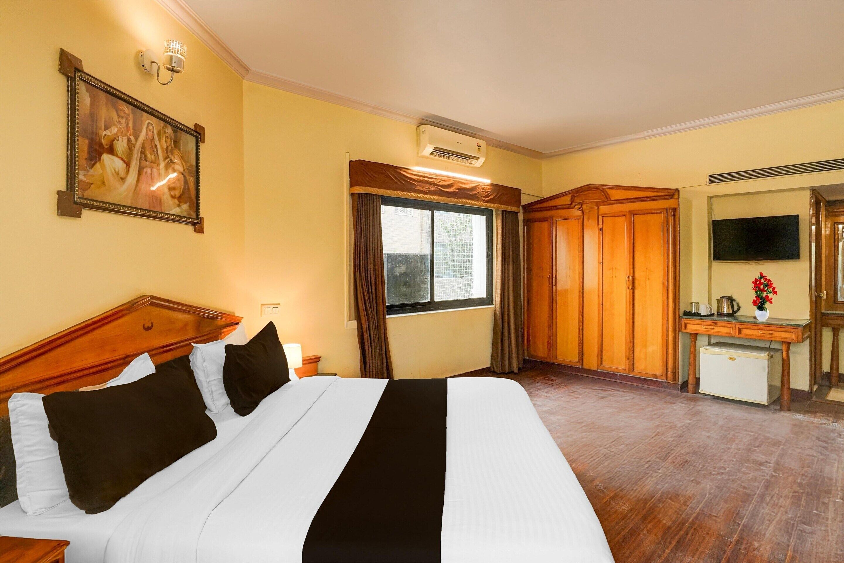 A hotel room with a bed, a TV, a desk, and a wardrobe.