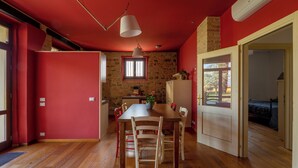 Uma área de refeições com mesa e cadeiras de madeira, luminária pendente e parede de pedra.