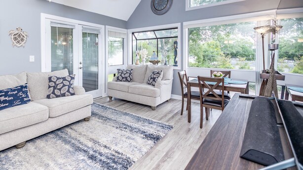 A modern living room with a sofa, coffee table, and dining area. - Your Shore Drive Escape Awaits at Arcadian Dunes 27-609 (Myrtle Beach)