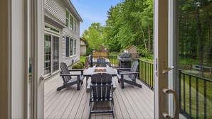 An outdoor deck with a table and chairs, a grill, and a view of a house and trees. - NEW Luxury Saratoga Track Rental: 4 miles to track, Hot tub, Sunroom, 8 beds! (Saratoga Springs)