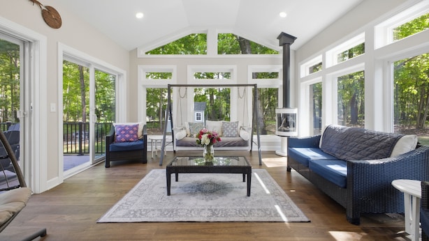 A spacious room with a large window, a ceiling fan, a glass coffee table, and a blue sofa. - NEW Luxury Saratoga Track Rental: 4 miles to track, Hot tub, Sunroom, 8 beds! (Saratoga Springs)