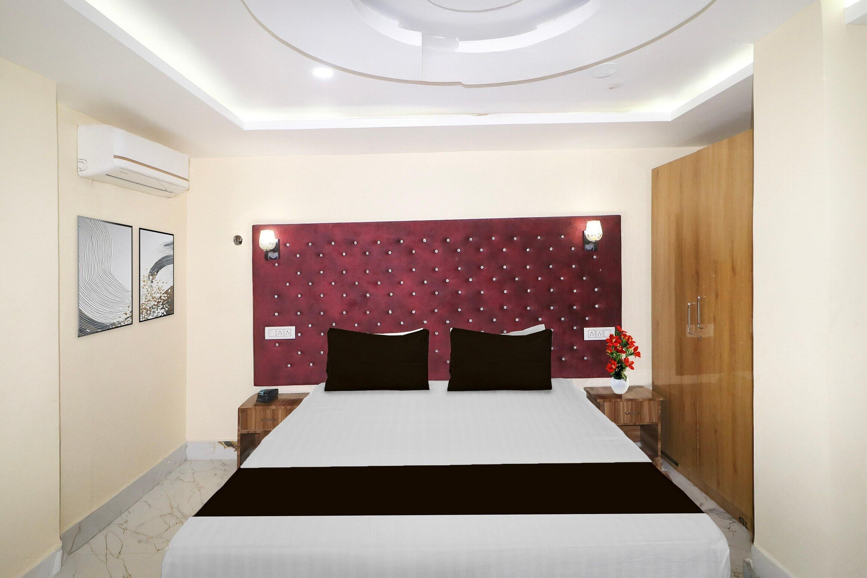 A hotel room with a bed, a headboard, a nightstand, a wardrobe, and a wall-mounted air conditioner.
