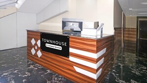 A reception desk with a sign reading 'Townhouse & Company-Serviced,' a staircase, and a polished marble floor. - Super Deluxe Room Hotel Rise And Dine (Dhanbad)