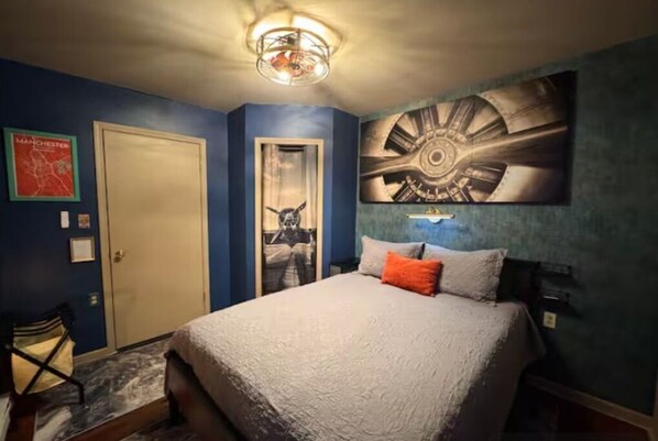 A bedroom with a bed, a door, a wall with a map, and a ceiling light fixture.