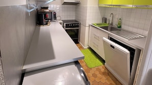 Uma cozinha compacta com micro-ondas, forno e máquina de lavar louça.