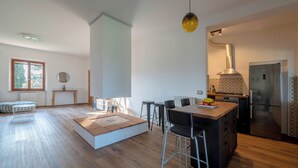 Eine moderne Küche mit Kochinsel, Barhocker, Kühlschrank und einer hängenden Leuchte.