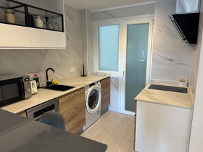 A compact kitchen with a microwave, toaster, sink, and washing machine. - Home of Wine & Comfort in the Heart of Haro (Haro)