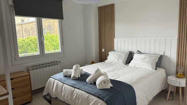 A bedroom with a bed, a bedside table, a radiator, a window with a view, and a ceiling light. - Home of Wine & Comfort in the Heart of Haro (Haro)