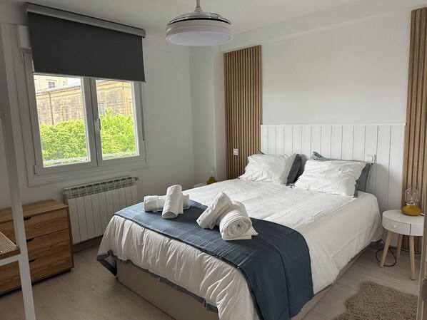A bedroom with a bed, a bedside table, a radiator, a window with a view, and a ceiling light. - Home of Wine & Comfort in the Heart of Haro (Haro)