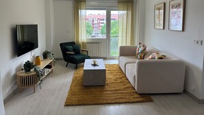 A modern living room with a flat-screen TV, a green armchair, a beige sofa, and a coffee table. - Home of Wine & Comfort in the Heart of Haro (Haro)
