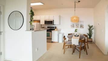 A compact kitchen with white cabinets, a microwave, and a dining area with a table and chairs.