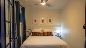 Une chambre à coucher avec un lit, un ventilateur de plafond et trois tableaux encadrés accrochés au mur.