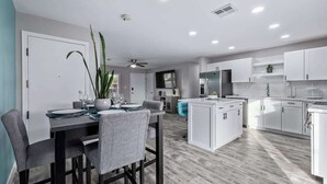 A modern kitchen with white cabinets, a dining area with a table and chairs, and a ceiling fan. - Family Fun Getaway Near ASU & Phoenix Zoo (Tempe)