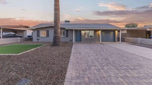 A residential house with a paved driveway, a lawn, and a palm tree. - Family Fun Getaway Near ASU & Phoenix Zoo (Tempe)