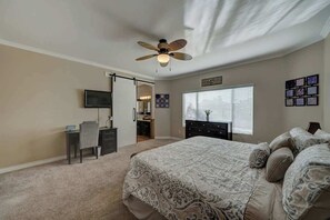 A bedroom with a bed, a desk, a chair, a television, a ceiling fan, and a window with blinds. - Chandler 4BR Getaway w/ Pool, Games & Fast Wi-Fi (Chandler)