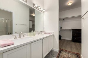 A modern bathroom with a large mirror, dual sinks, and a walk-in closet. - Modern 2BR Townhouse |Shared Pool, Gym, Spa & More (Phoenix)