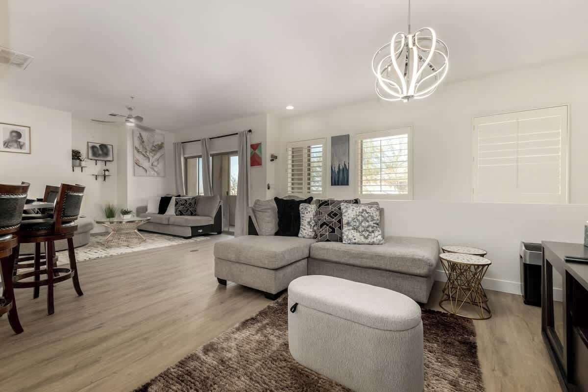 A modern living room with a sectional sofa, a round coffee table, and a unique chandelier.