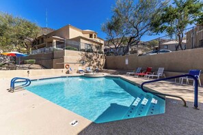 A swimming pool with a blue water feature, surrounded by lounge chairs and a building in the background. - Modern 2BR Townhouse |Shared Pool, Gym, Spa & More (Phoenix)
