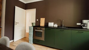 Una cocina con armarios verdes, una puerta blanca y una encimera con un tostador y una cafetera.