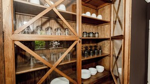 Un mueble de madera con estantes que contienen frascos de vidrio, platos y cuencos.