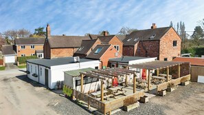 A residential area with multiple houses, a small building with a flat roof, and a wooden structure with benches. - The Winners Enclosure: Countryside Flat Above a Village Pub (Withington)
