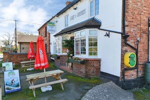 Eine Kneipe namens 'Hare & Hounds' mit Außenbestuhlung und einem Schild mit der Aufschrift 'Your Village Pub'.