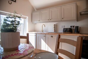 Eine Küche mit Holzausstattung, einem Spülbecken und einer Arbeitsplatte mit Radio und Kaffeemaschine.
