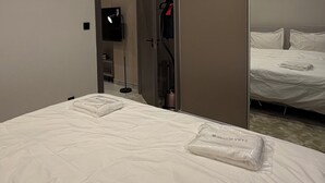 Ett hotellrum med en säng, en garderob, en TV och en luftkonditioneringsanläggning.