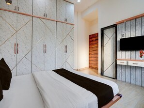 A bedroom with a bed, wardrobe, TV, and a small desk area. - Deluxe With Twin Bed Kaveri Executive Lodging (Rajgurunagar)