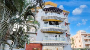 A multi-story building with a glass facade, a balcony on the second floor, and a sign that reads 'Collection.' - Deluxe With Twin Bed Kaveri Executive Lodging (Rajgurunagar)