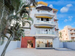 A multi-story building with a glass facade, a balcony on the second floor, and a sign that reads 'Collection.' - Deluxe With Twin Bed Kaveri Executive Lodging (Rajgurunagar)