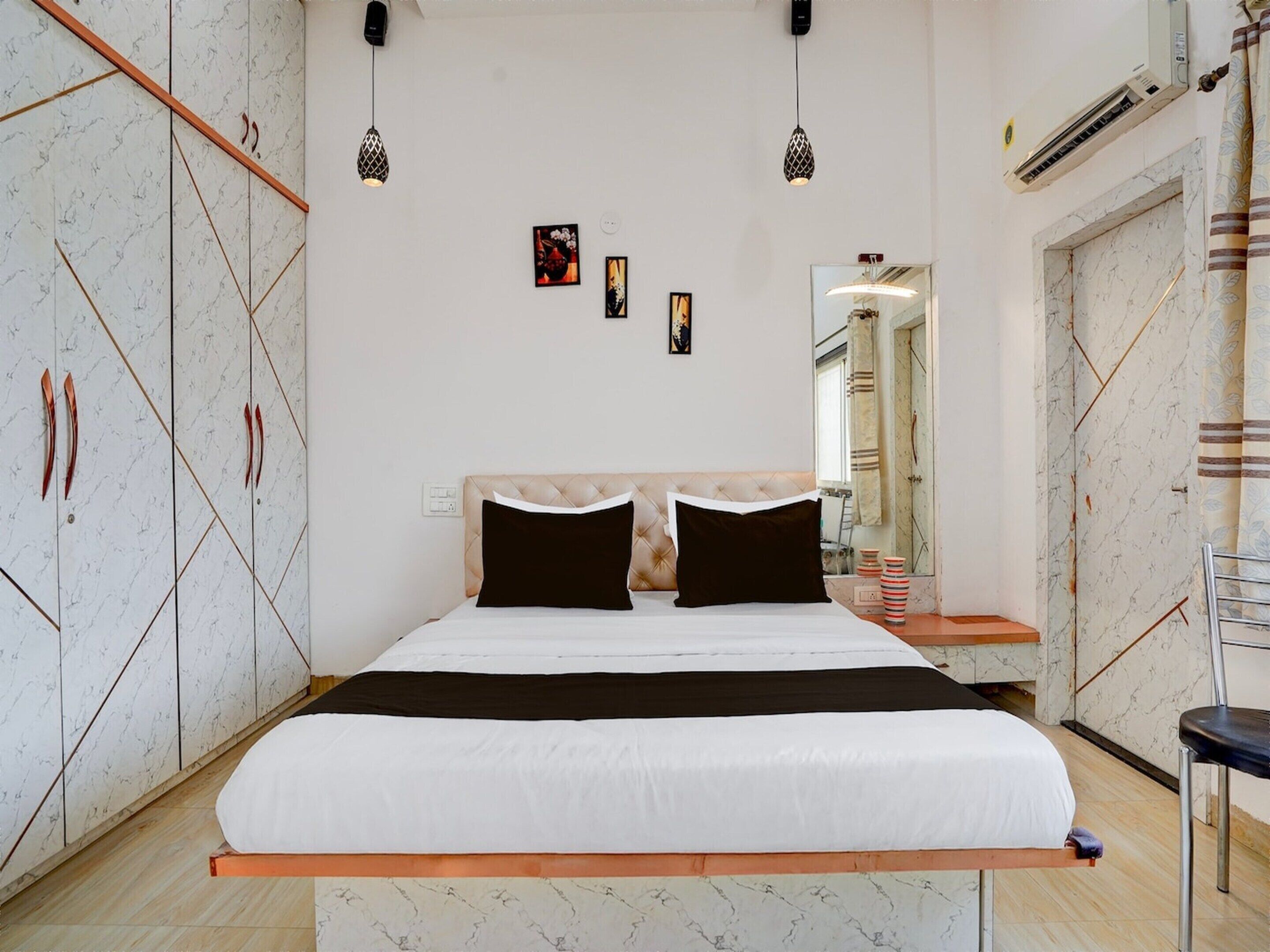 Une chambre à coucher avec un lit, une armoire, des lampes suspendues et un miroir.