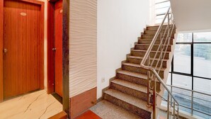 A staircase with a metal handrail, a wooden door, and a textured wall. - Deluxe With Twin Bed Kaveri Executive Lodging (Rajgurunagar)
