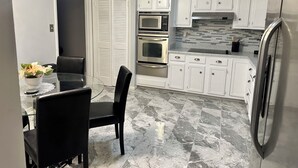A modern kitchen with white cabinets, stainless steel appliances, and a marble floor. - 3-bedroom house in peaceful Fort Washington with AC comfort (Fort Washington)