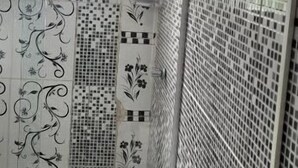 Ein Badezimmer mit Toilette, Dusche und Waschbecken. Die Wände sind mit einem Mosaikmuster gefliest.