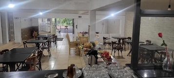 Uma sala de jantar com mesas e cadeiras, um serviço de buffet e vista para o exterior.